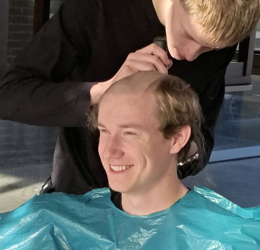 Ilya die Lex aan het kaal scheren is, Ilya is gefocust en Lex heeft een brede lach op zijn gezicht